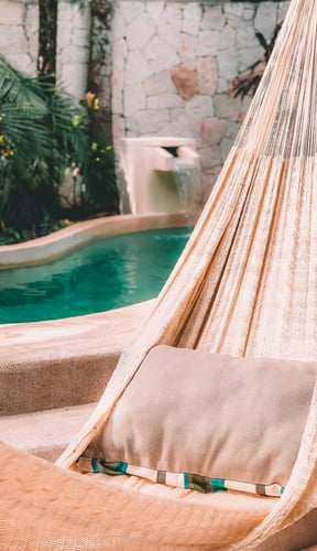 Hammock hanging in a private pool villa with tropical stone walls and greenery