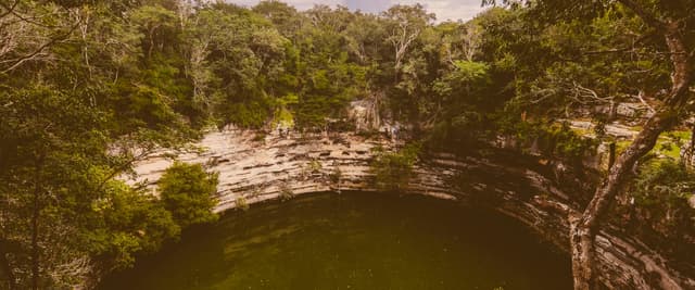 Aerial view of a cenote surrounded by dense Yucatan jungle canopy
