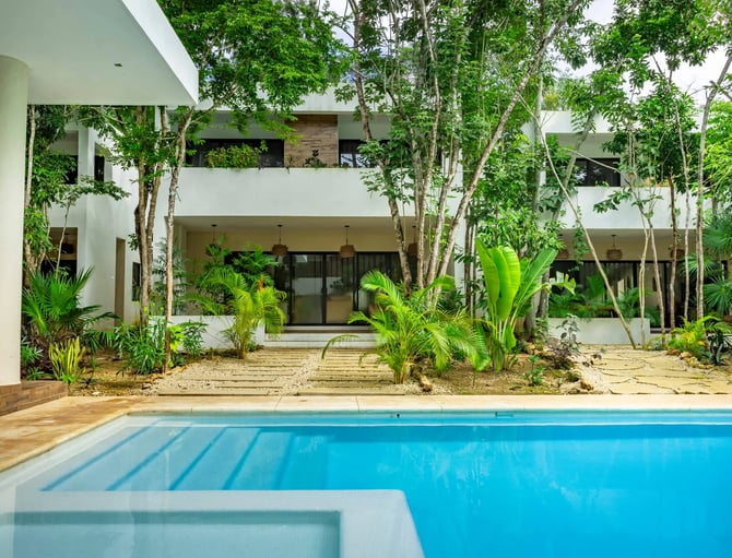 Modern white house with swimming pool, tropical trees, and sandy courtyard