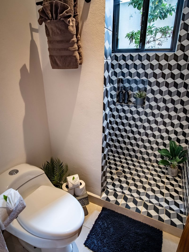 Small bathroom with a toilet and geometric tiled shower.
